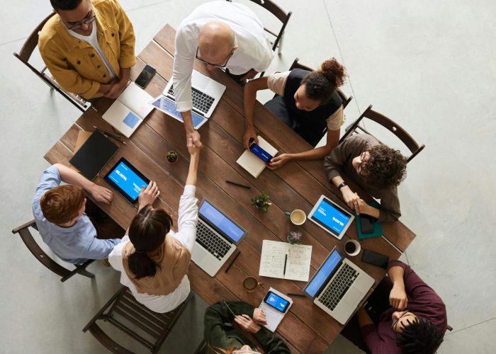 Top view of a diverse team collaborating in an office setting with laptops and tablets, promoting cooperation.